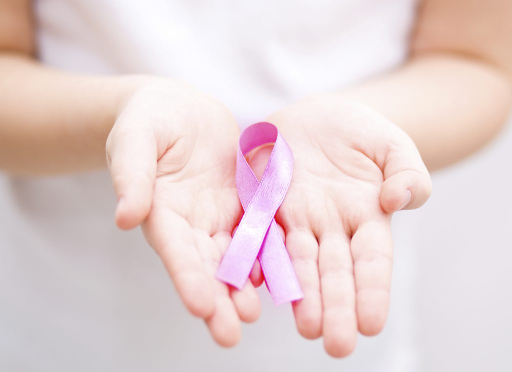 healthcare and medicine concept - girl hands holding pink breast cancer awareness ribbon